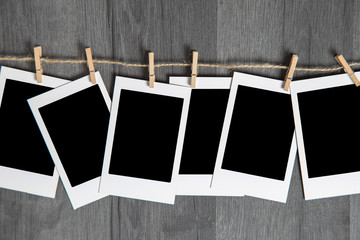 Blank vintage polaroid instant photos frame with empty space hanging on rope on wooden background. Copy and paste your photo