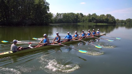 Rowing team summer training. 8 athletes rowers in a boat in the river Dnipro. City area in Kiev, Ukraine - Powered by Adobe