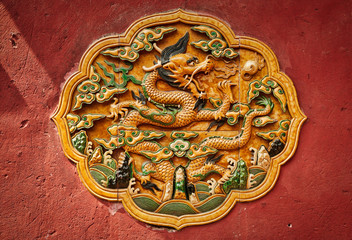Fretwork in the form of a dragon on the red wall in the Forbidden City. Beijing,