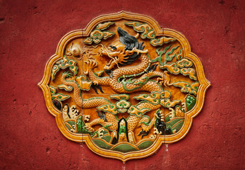Fretwork in the form of a dragon on the red wall in the Forbidden City. Beijing,