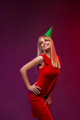 Event, party, Birthday, Christmas or New Year celebrating concept . Having fun. Young pretty blond woman in red dress and birthday hat is laughing. Studio portrait with bright background. Copy space