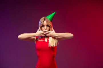 Woman in red dress surprised and covers her mouth with her hands. Beautiful girl with blond hair surprised and shocked looks on you . Facial expressions