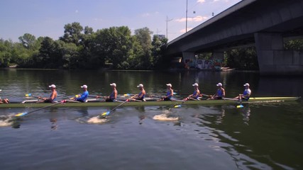 Rowing team summer training. 8 athletes rowers in a boat in the river Dnipro. City area in Kiev, Ukraine