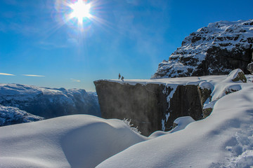 two people enjoying the sun on Preikestolen in winter, Stavanger, Norway