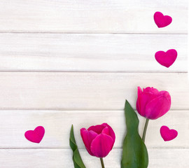 Decoration of Valentine day. Beautiful pink tulips and pink hearts on background of white painted wooden planks with space for text. Top view, flat lay