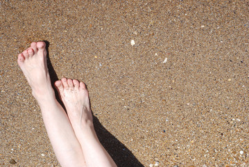 Female feet on the sandy beach of the sea