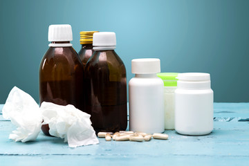 Dirty paper handkerchief and syrup bottles and drug on blue wood table, influenza concept