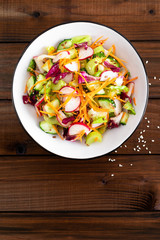 Healthy vegetarian vegetable salad with fresh raw radish, carrot, celery, lettuce, sesame and flax seeds. Vegan diet food
