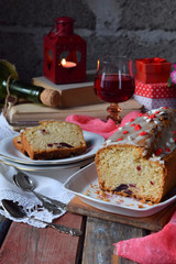 Dried fruit cake with raisins, apricots, cherry and glass of red wine, bottle and flower rustic wooden background. Valentines day still life. Sliced freshly baked fruitcake. Copy space for text