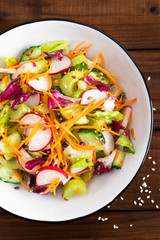 Healthy vegetarian vegetable salad with fresh raw radish, carrot, celery, lettuce, sesame and flax seeds. Vegan diet food