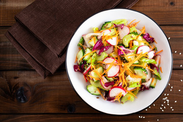 Healthy vegetarian vegetable salad with fresh raw radish, carrot, celery, lettuce, sesame and flax seeds. Vegan diet food