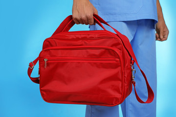 Male doctor with first aid kit on color background, closeup. Medical object