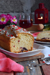Dried fruit cake with raisins, apricots, cherry and glass of red wine, bottle and flower rustic wooden background. Valentines day still life. Sliced freshly baked fruitcake. Copy space for text