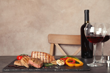 Grilled meat served with garnish, sauce and wine on table. Space for text