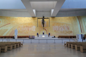 Huge hall with rows of seats an an altar with a big artwork in the background