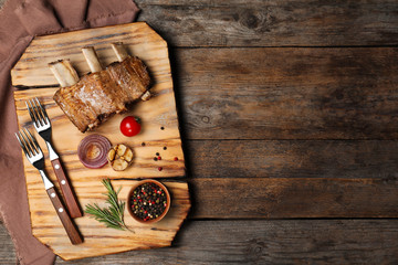 Flat lay composition with roasted ribs and space for text on wooden background. Tasty meat