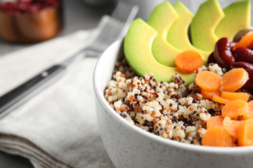 Healthy quinoa salad with vegetables in bowl on table, closeup. Space for text