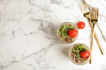 Healthy quinoa salad with vegetables in jars and forks on table, top view. Space for text