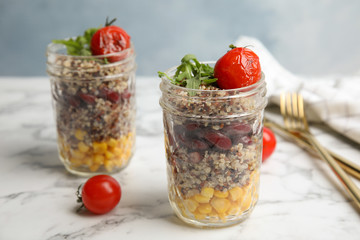 Jars with healthy quinoa salad and vegetables on table. Space for text