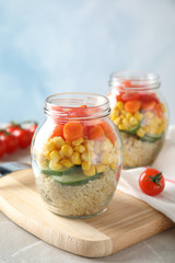 Jars with healthy quinoa salad and vegetables on table. Space for text