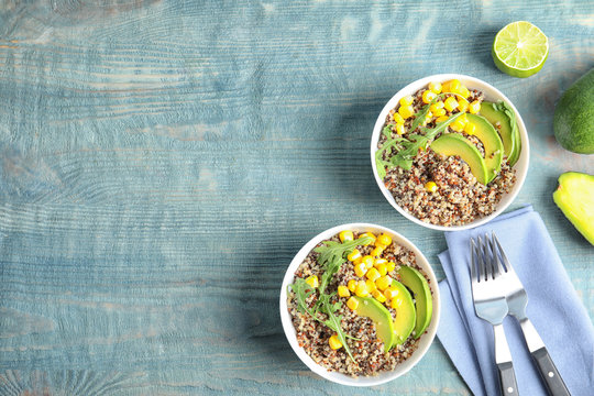 Healthy quinoa salad with vegetables in bowls served on wooden table, top view. Space for text