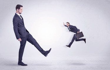 Big man in suit kicking out little himself out with simple white wallpaper
