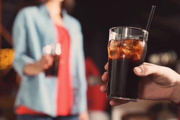 Man holding glass of cola in bar, closeup. Space for text