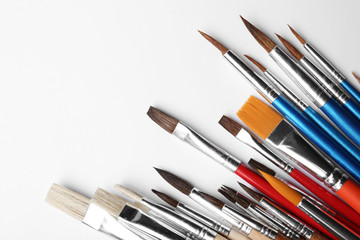Fototapeta premium Different paint brushes on white background, top view. Space for text