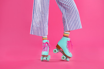 Young woman with retro roller skates on color background, closeup