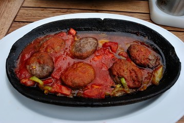 Turkish meatballs cooked in a tile pot with onion, tomato and pepper sauce - Kiremitte Kofte