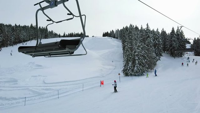 ROGLA, SLOVENIA, 2019.01.29: View from ski lift beside ski slope with skiers. Filming beautiful ski resort on cold sunny winter day.