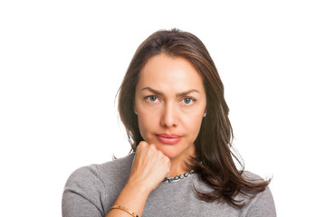 Upset unsatisfied woman standing with hand on chin and looking at camera isolated over white background