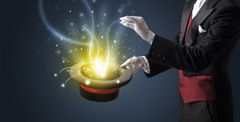 Magician hand conjure with wand  light from a black cylinder