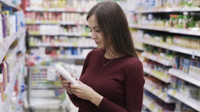 Attractive woman takes shower gel and sniffs it in supermarket, emotion like the product