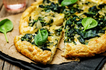Spinach Ricotta Galette with fresh spinach leaves on a wood background