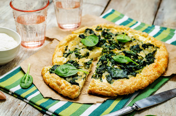 Spinach Ricotta Galette with fresh spinach leaves on a wood background