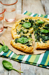 Spinach Ricotta Galette with fresh spinach leaves on a wood background