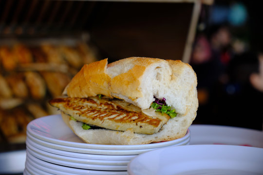 Traditional fish sandwich served on the dock of Eminonu area of Istanbul.  Sandwich is main focus with grill and sit down area off focus in back