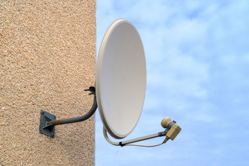 blue sky on its background white old satellite dish on a multi-storey building