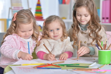 Portrait of three cute little girls drawing