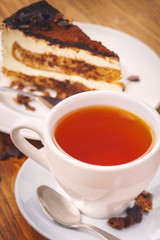 Cup of fresh hot tea with delicious piece of chocolate cake on the wooden table