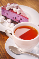 Cup of fresh hot tea with delicious piece of blueberry cake on the wooden table
