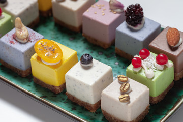 Dessert.  Assorted fruit pastries made from natural products on a beautiful, green plate on a white background. Cakes with fresh berries and nuts.