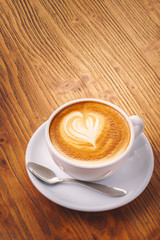 Cup of fresh cappuccino coffee on the wooden table