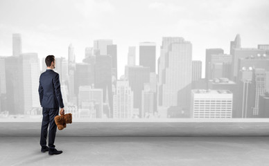 Businessman standing with his back on a roof with objects in his hand
