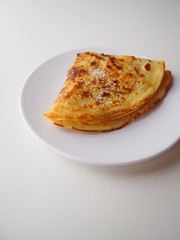 Traditional french crepe (or pancake) on a white plate, with sugar on top (called crêpe Suzette), white background