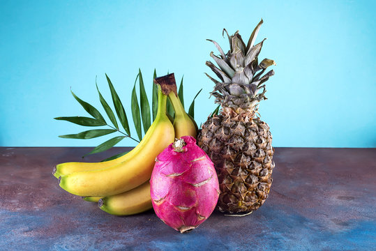 Assorted tropical fruits pineapple, mango, dragon fruit, on stone background. Group of exotic tropical fruits. Vegetarian healthy concept