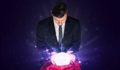 Young businessman sitting with crystal ball in action