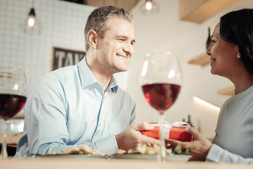Smiling woman giving a present to man