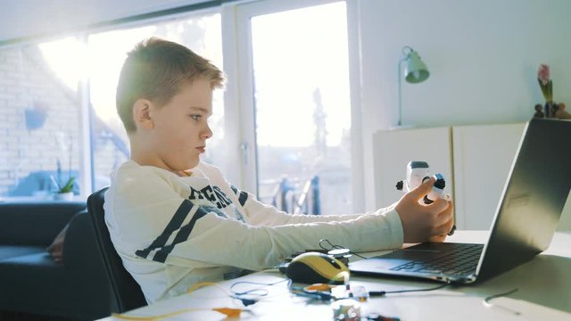 Boy plays with a small robot and day dreams as the sun shines through windows